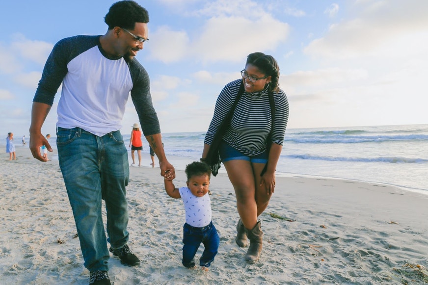 A family with their child walking along the beach